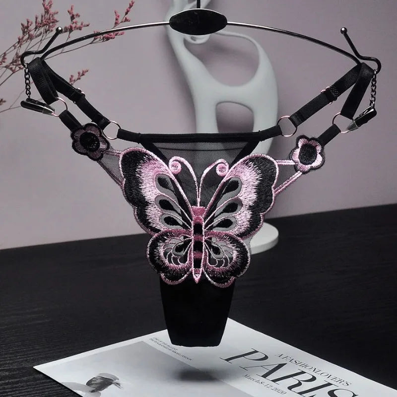 Black adjustable thong with pink-and-black butterfly embroidery, displayed on a hanger