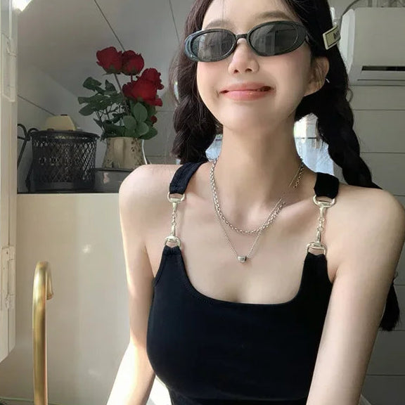 Front-facing model wearing a black slim-fit tank top with chain-linked straps