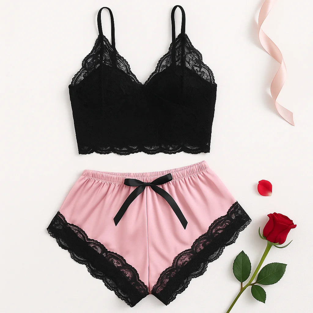 Flat lay of a black lace camisole and pink satin shorts with black trim