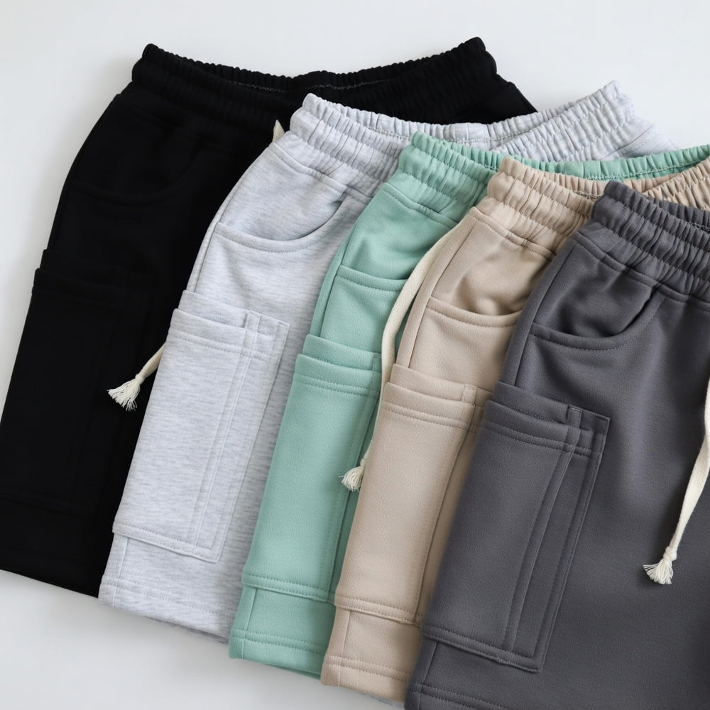 Overlapping casual shorts in black, light gray, mint, beige, and charcoal, shown from above