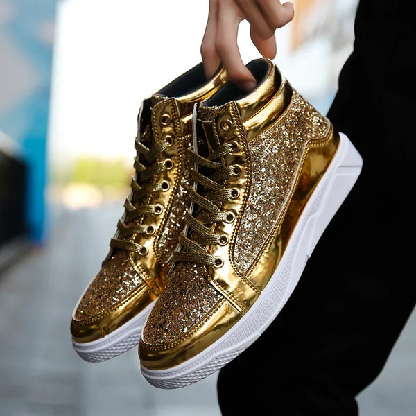 Hand holding a pair of glittering gold high-top sneakers with white soles