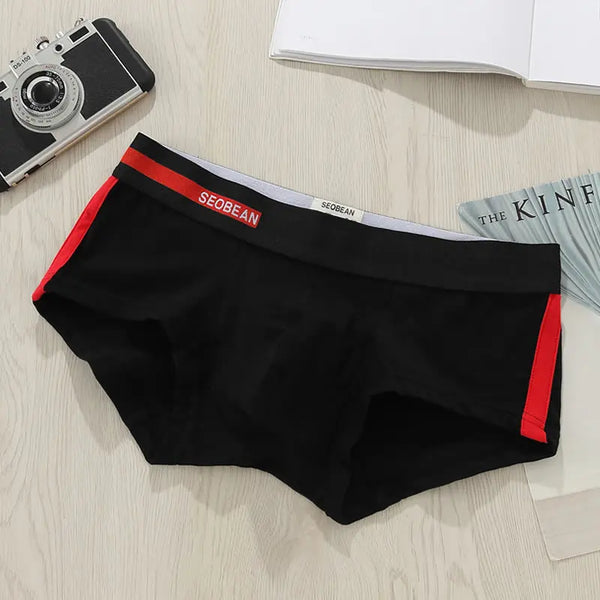 Flat lay of black men's boxer briefs with red side panels and a red SEOBEAN waistband