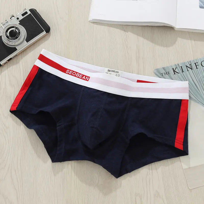 Flat lay of navy men's boxer briefs with red side stripes and a white logo waistband