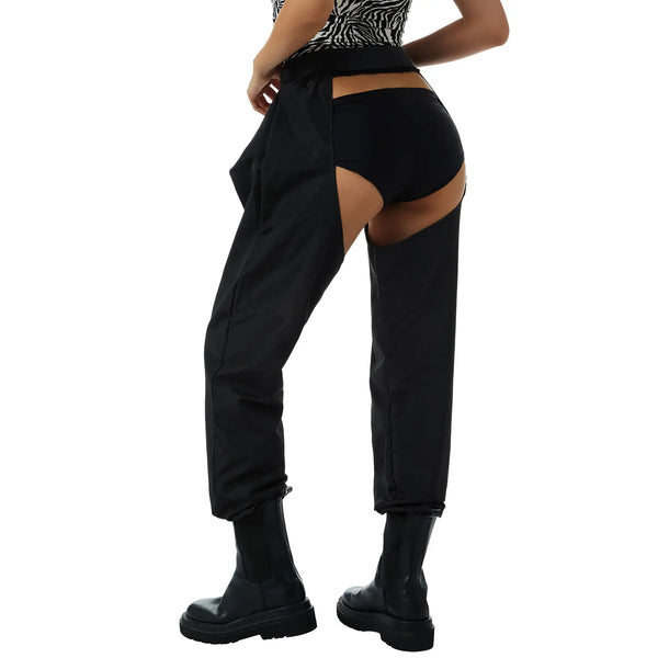 Rear view of black buckle cargo pants with cutout hips, worn with black briefs and boots