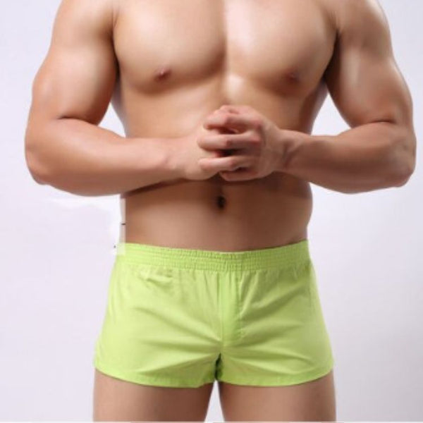 Front view of a shirtless model wearing bright lime-green elastic-waist shorts