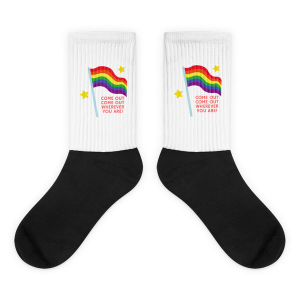 Pair of black-and-white socks with rainbow flags, yellow stars, and red “COME OUT” text