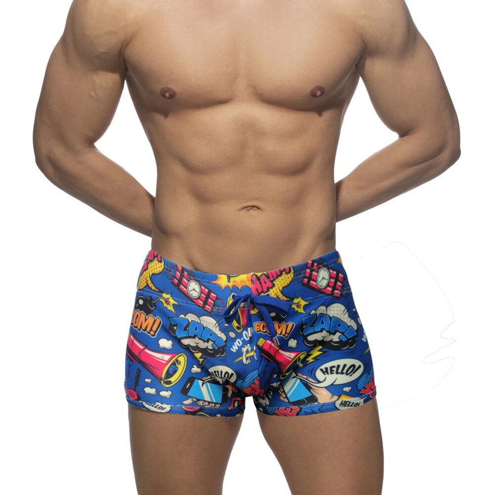 Front view of a model wearing blue comic-print swim shorts with a drawstring
