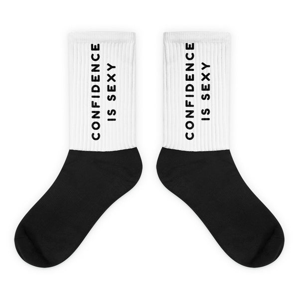 Pair of black-and-white crew socks reading “CONFIDENCE IS SEXY” on the ribbed cuffs