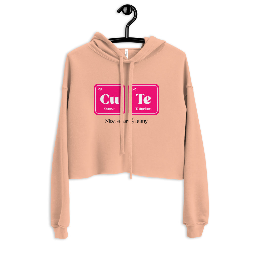 Front view of a peach cropped hoodie on a hanger with a Cu and Te graphic and partial text