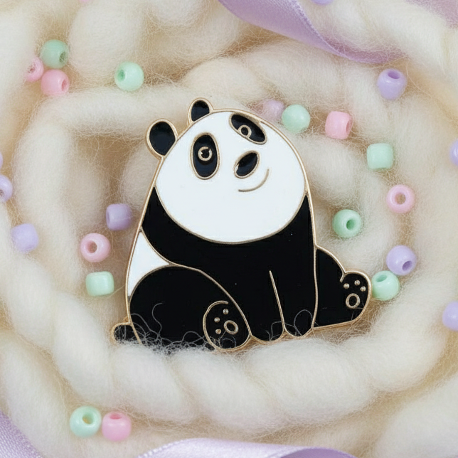 Cute Panda Enamel Pin in black and gold, resting on wool with pastel beads and lilac ribbon