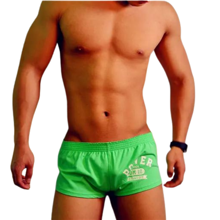 Front-facing shirtless model wearing bright green boxer shorts with a white printed graphic
