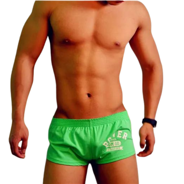 Front-facing shirtless model wearing bright green boxer shorts with a white printed graphic