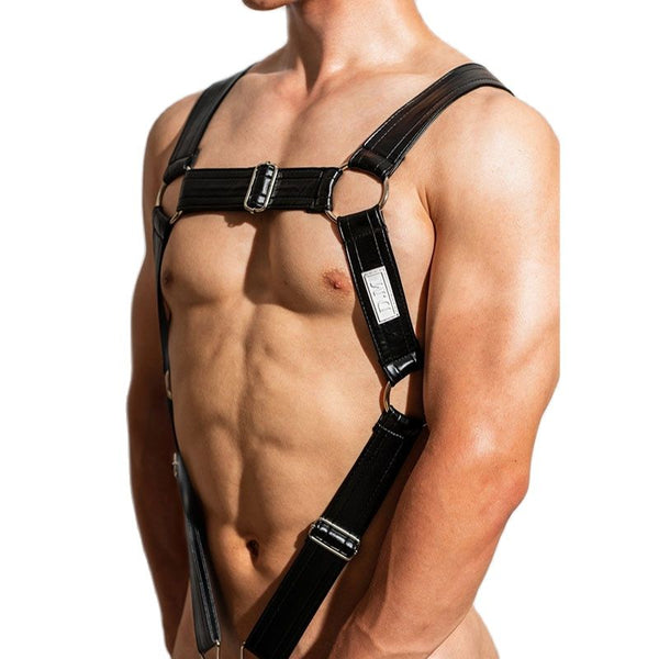 Cropped model wearing a black leather chest harness with adjustable straps and metal rings