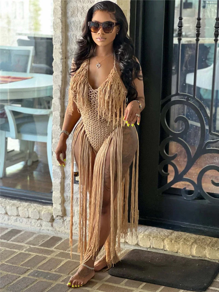 Model wearing a tan crocheted one-piece with long fringe in a doorway