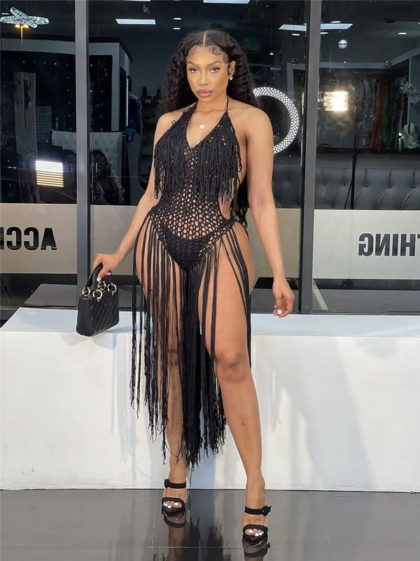Model wearing a black fringed crochet halter dress with a deep cutout and long hem