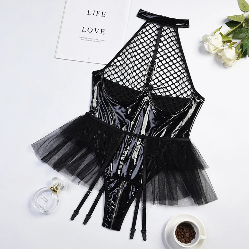 Flat lay of a black glossy PU bodysuit with fishnet cups, tulle skirt, and garter straps