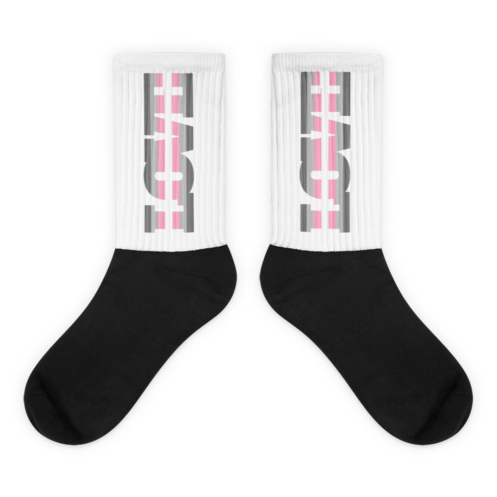 Pair of black crew socks with white ribbed cuffs and gray-and-pink abstract graphics