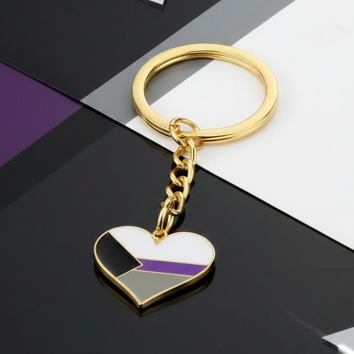 Gold heart keychain with the demisexual pride flag on a black-and-white surface