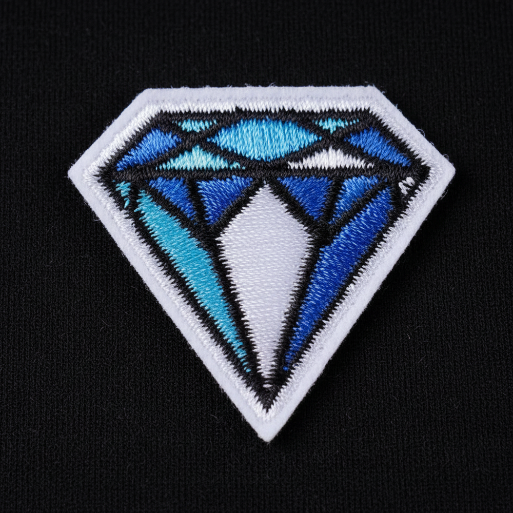 Diamond-shaped embroidered patch with blue, cyan, white, and black geometric facets