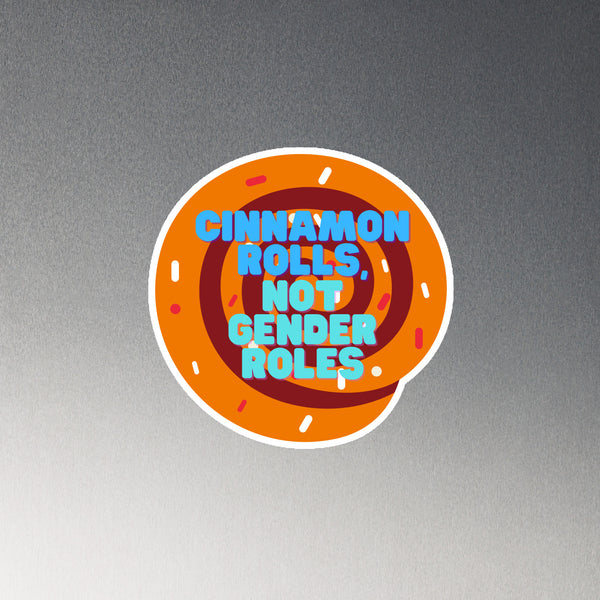 Round orange magnet reading “CINNAMON ROLLS, NOT GENDER ROLES” on a gray surface