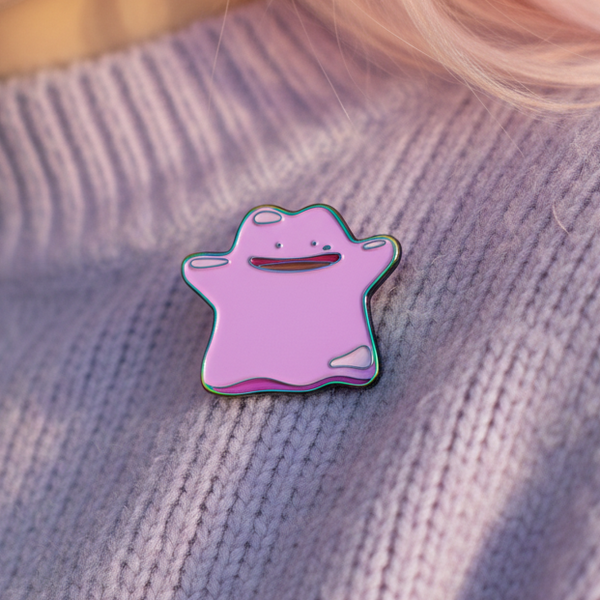 Pink Ditto character enamel pin resting on a lavender knitted sweater