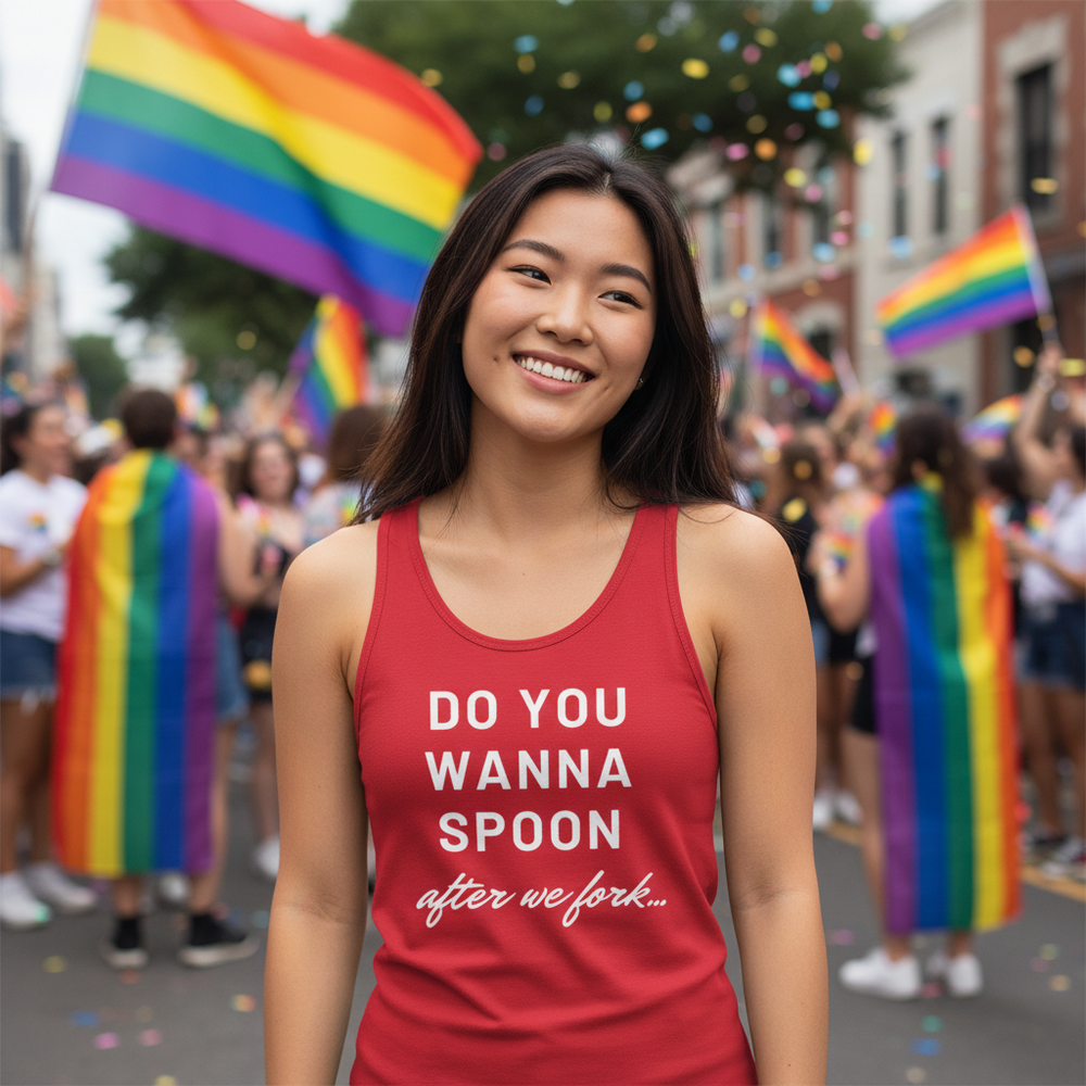 Unisex tank top with "Do You Wanna Spoon After We Fork" worn by a smiling queer at a vibrant pride parade with rainbow flags.