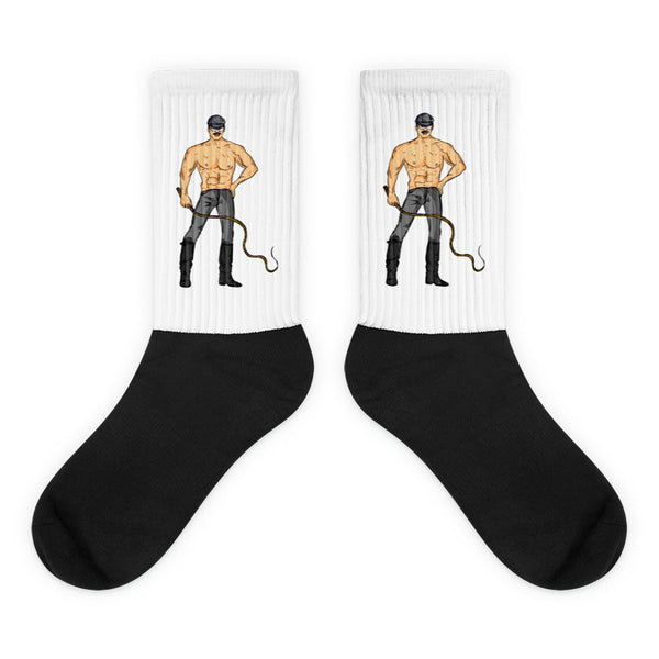 Pair of white-and-black socks featuring shirtless cartoon men holding whips