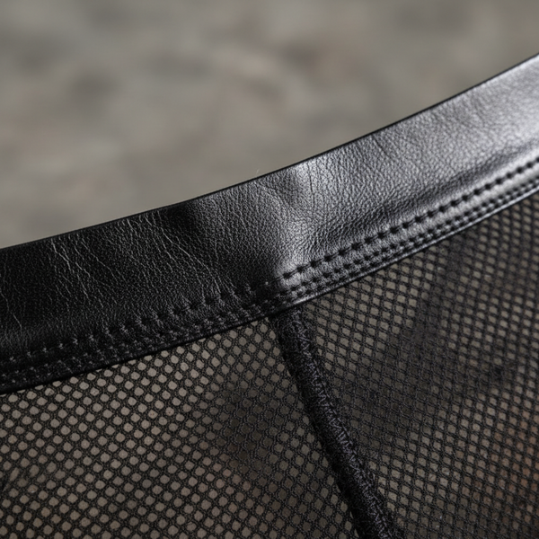 Close-up of black leather trim stitched to black diamond-pattern mesh fabric