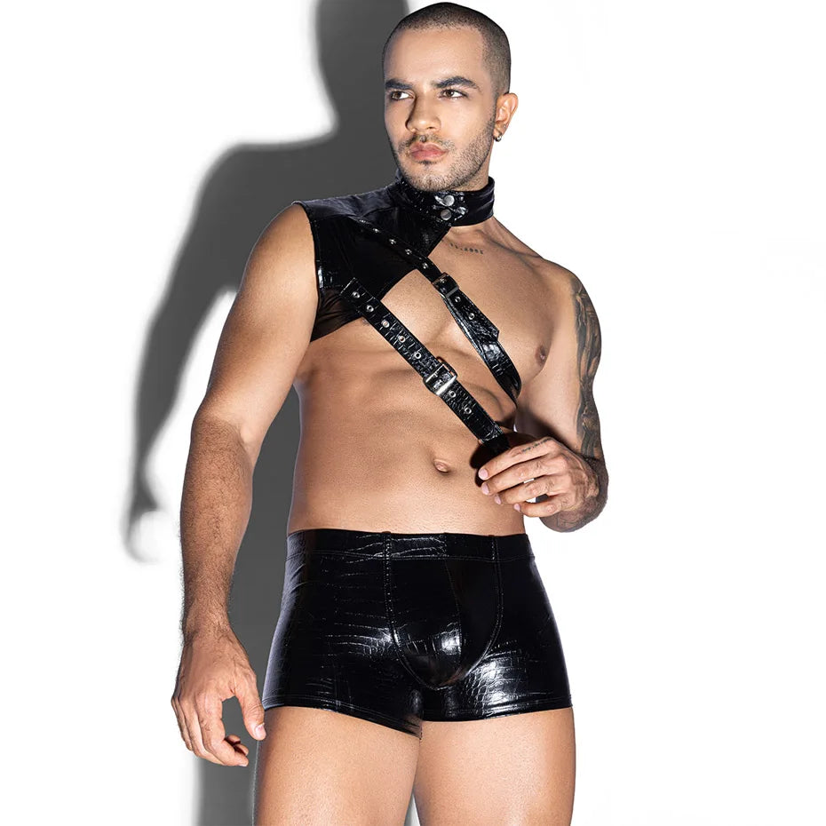 Front-facing model wearing a glossy black chest harness, collar, and fitted shorts