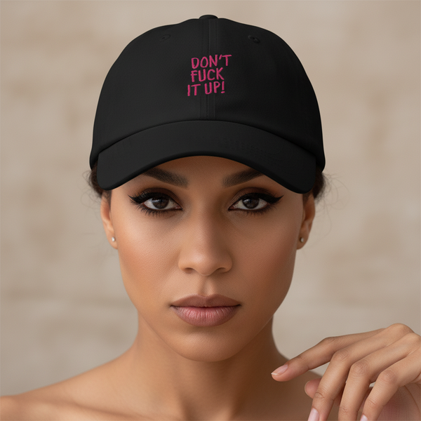 Black baseball cap with bold pink “Dont Fuck It Up!” slogan, worn by a femme with winged liner and nude lips
