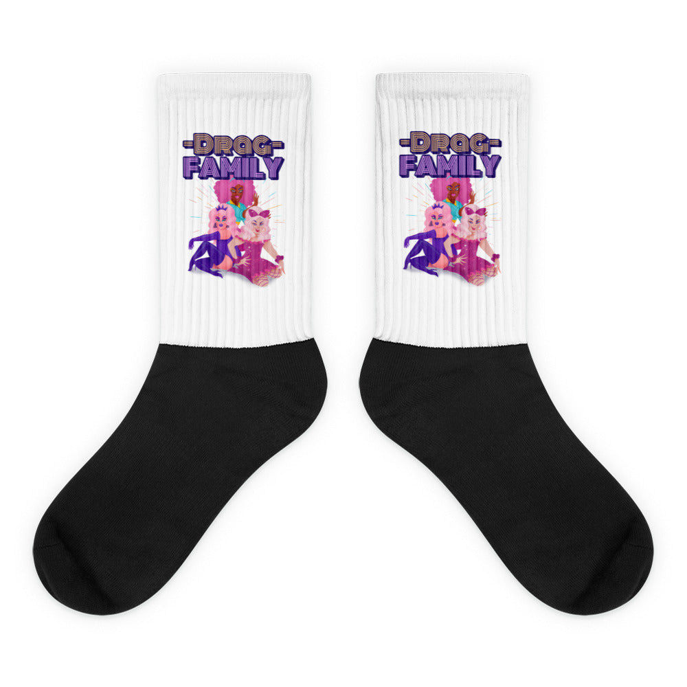 Pair of black-and-white socks with “DRAG FAMILY” text and three colorful drag performers