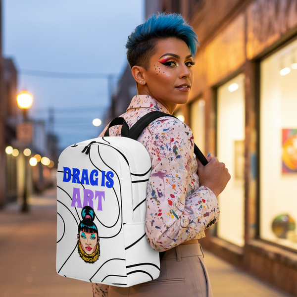 Drag Is Art Minimalist Backpack with “DRAG IS ART” slogan and a stylized drag queen, worn by a blue-haired person at dusk