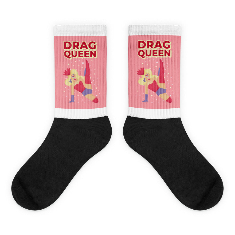 Pair of black socks with pink cuffs reading “DRAG QUEEN” and a cartoon performer