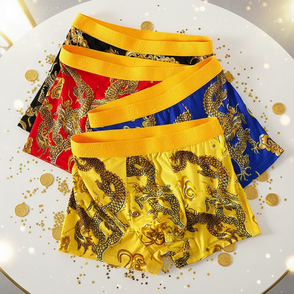 Four colorful dragon-print boxer shorts layered on a white tabletop with gold confetti