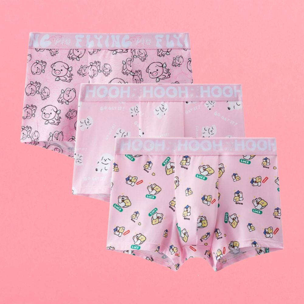 Three pink cartoon-print boxer briefs arranged overlapping on a pink background