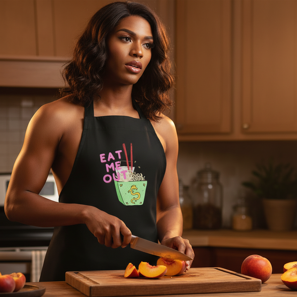 Model slicing peaches in a kitchen while wearing a black “EAT ME OUT” noodle-box apron