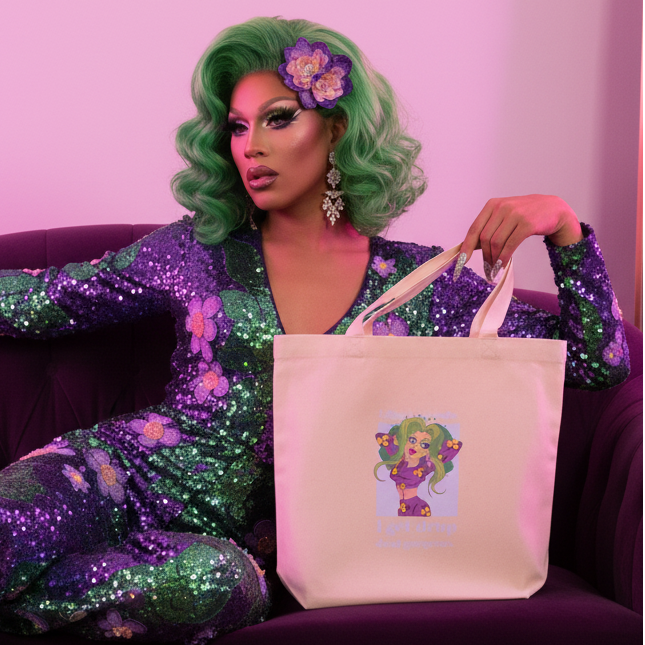 I Get Drop Dead Gorgeous Eco Tote Bag," with an illustrated character, held by a person with green hair and bold makeup on a purple couch. Their sparkling outfit and statement earrings pop in the pink-lit room—serving unapologetic queer energy.