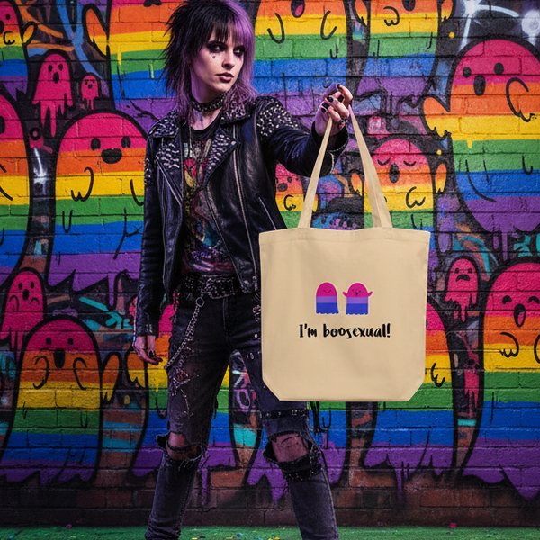Person in punk-style clothing holds a beige tote reading “I’m boosexual!” with two pink ghost icons.