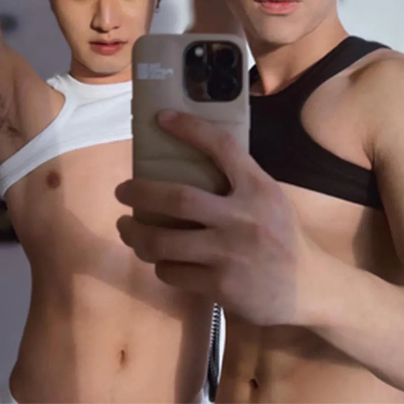 Mirror selfie showing two cropped asymmetrical tops, one white and one black