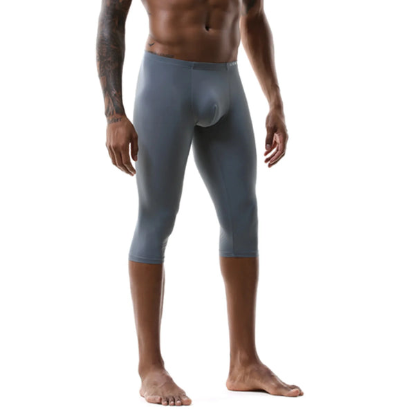 Front view of a shirtless model wearing gray, below-knee athletic leggings