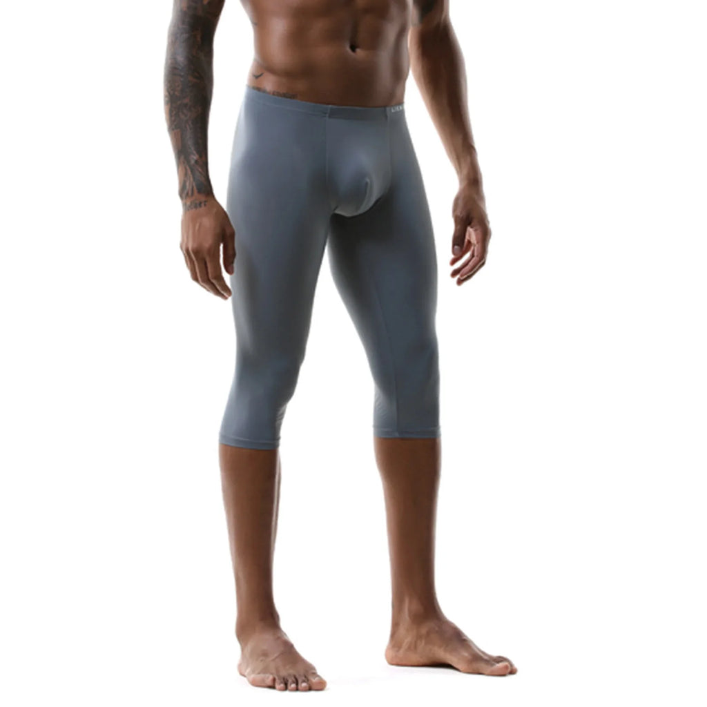 Front view of a shirtless model wearing gray, below-knee athletic leggings