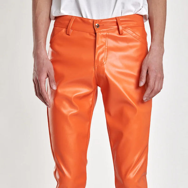 Front view of a model wearing bright orange fitted faux-leather pants