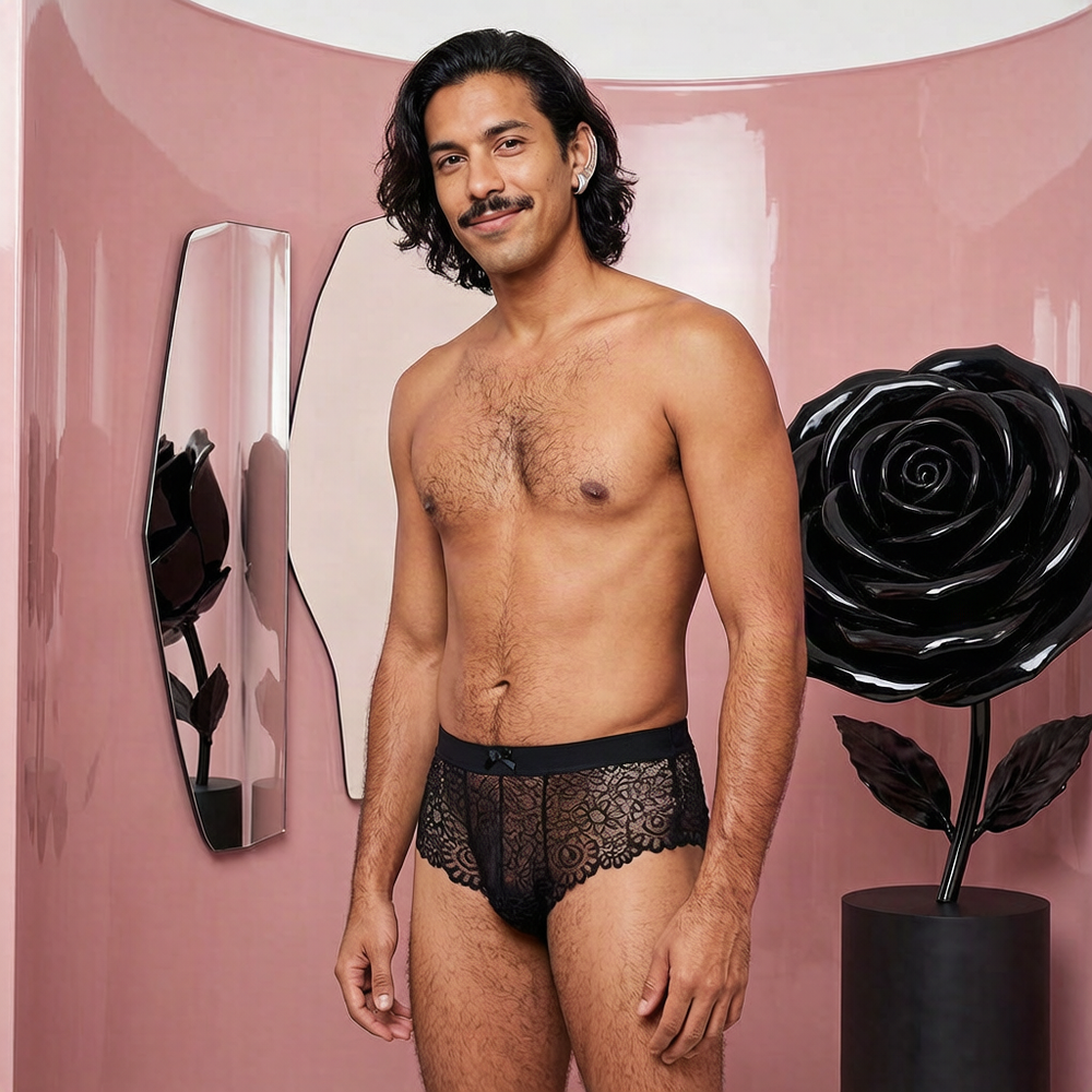 Adult model wearing black Embrace The Lace floral panties with a bow and scalloped edges in a pink sculptural salon
