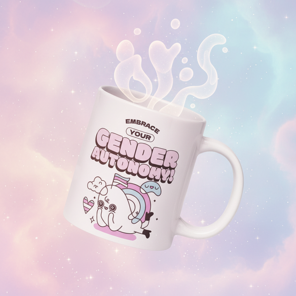Angled white mug reading “EMBRACE YOUR GENDER AUTONOMY!” with a cute rainbow-accented character
