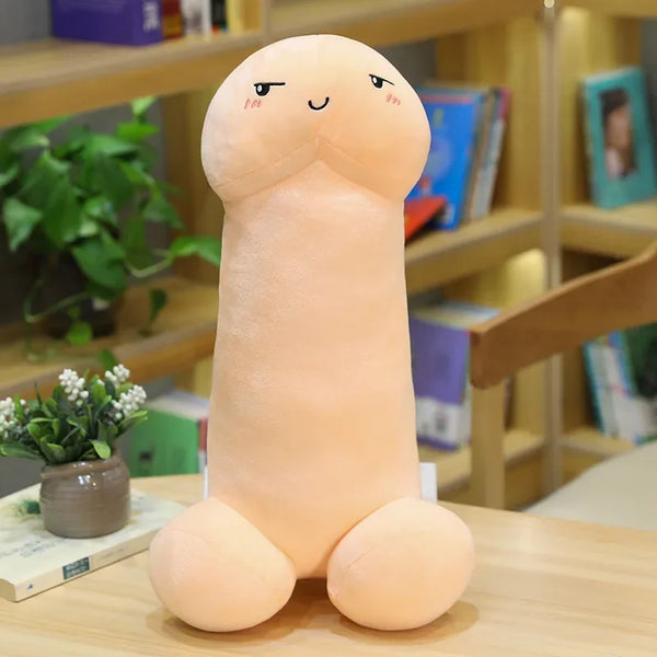 Front-facing plush penis pillow with a cute embroidered face on a table