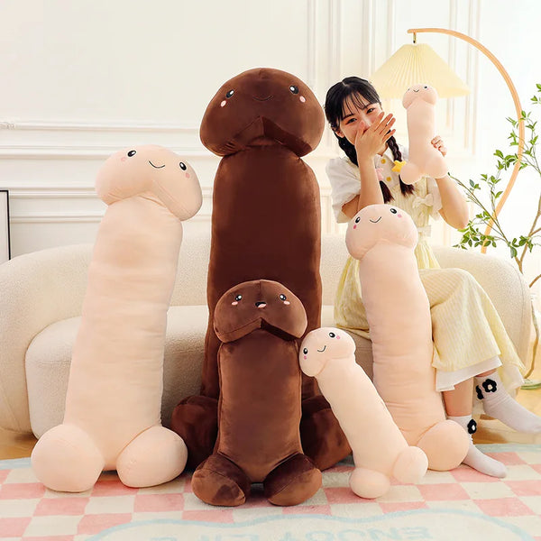 Person seated beside several smiling penis-shaped plush pillows in cream and brown