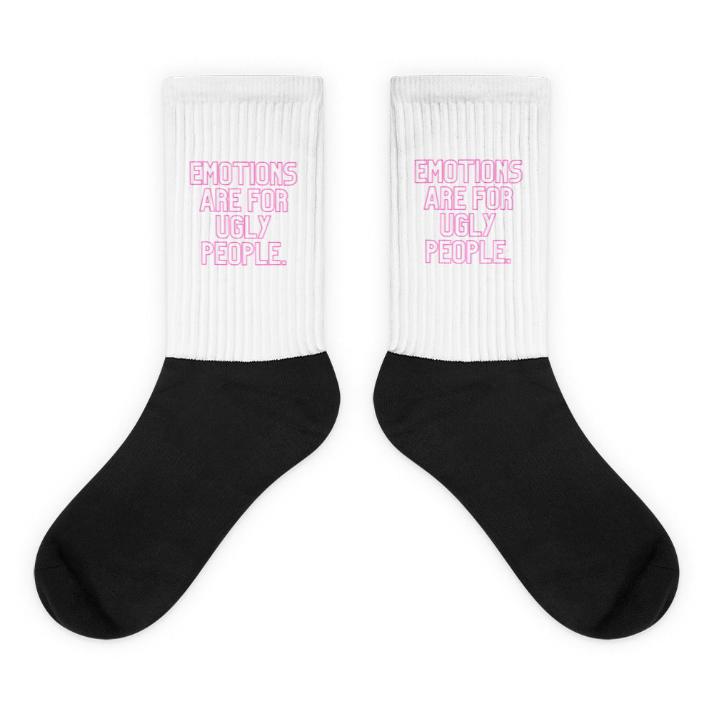 Pair of black crew socks with white ribbed cuffs reading “EMOTIONS ARE FOR UGLY PEOPLE.”