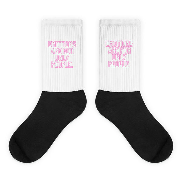 Pair of black crew socks with white ribbed cuffs reading “EMOTIONS ARE FOR UGLY PEOPLE.”