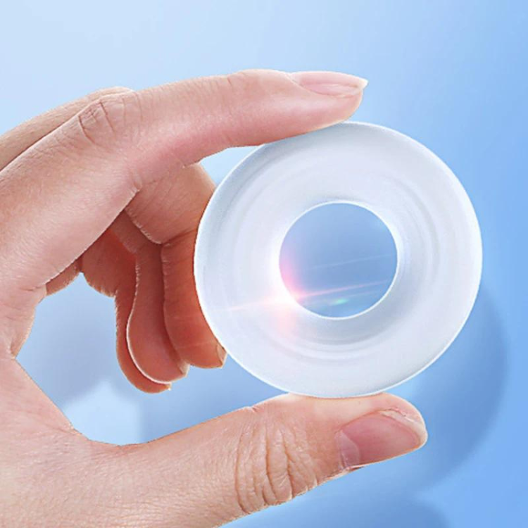 Top-down close-up of a translucent white silicone cock ring held between fingers