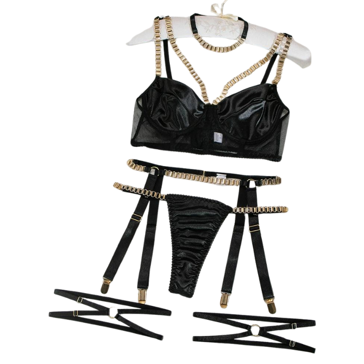 Flat lay of a black satin lingerie set with gold-tone chain straps and leg harnesses